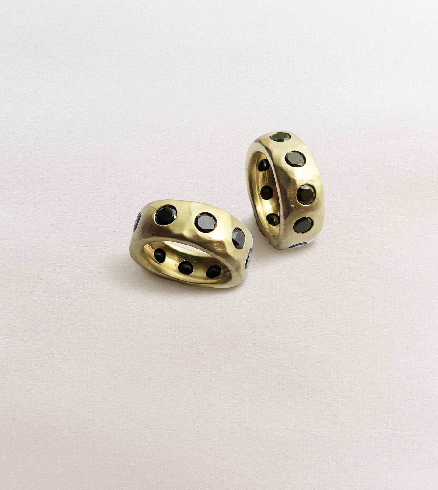 Two wide 18k yellow gold bands with black diamonds flush-set around a hand-carved, textured surface