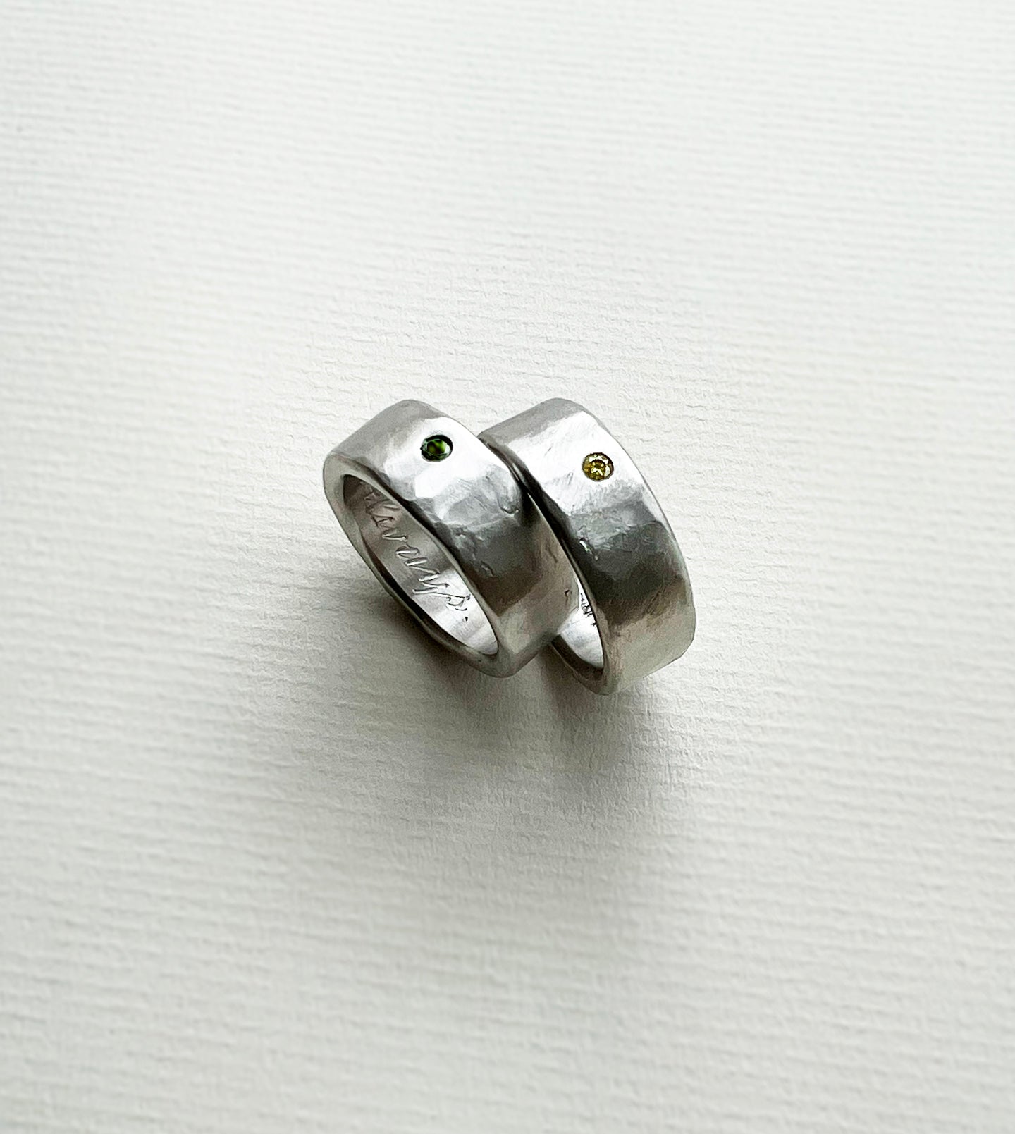 Pair of hand-carved platinum men's wedding bands with flush-set green sapphire and yellow diamond, hand-engraved inside
