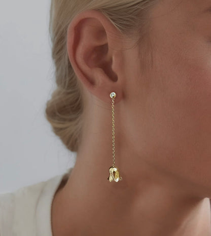 Gold lily-of-the-valley drop earring worn on the ear, a diamond stud with a chain and bell flower