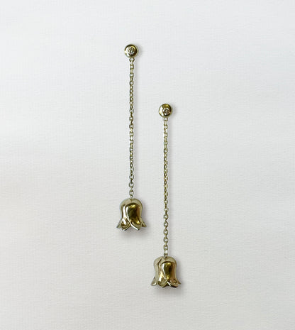 Pair of gold lily-of-the-valley drop earrings on paper, diamond studs with chains and bell flowers