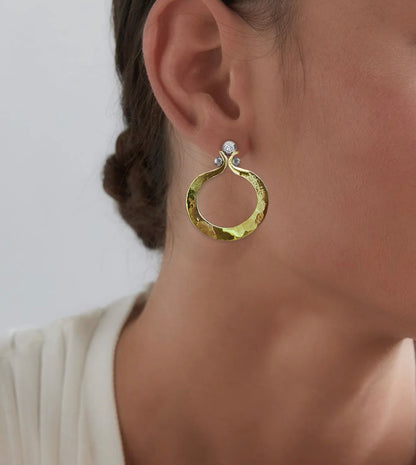 Hand-forged yellow gold diamond hoop earring worn on the ear, with a diamond set in an oxidized silver ball