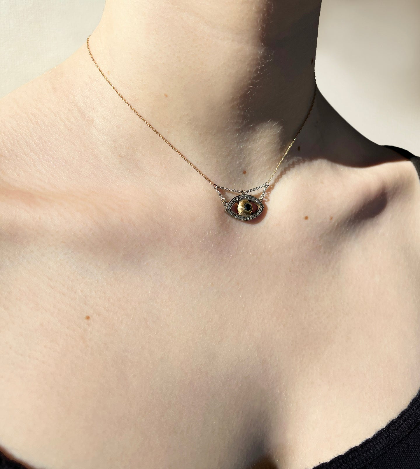 Evil eye necklace pendant detail, brushed yellow gold iris within a pavé white gold eye