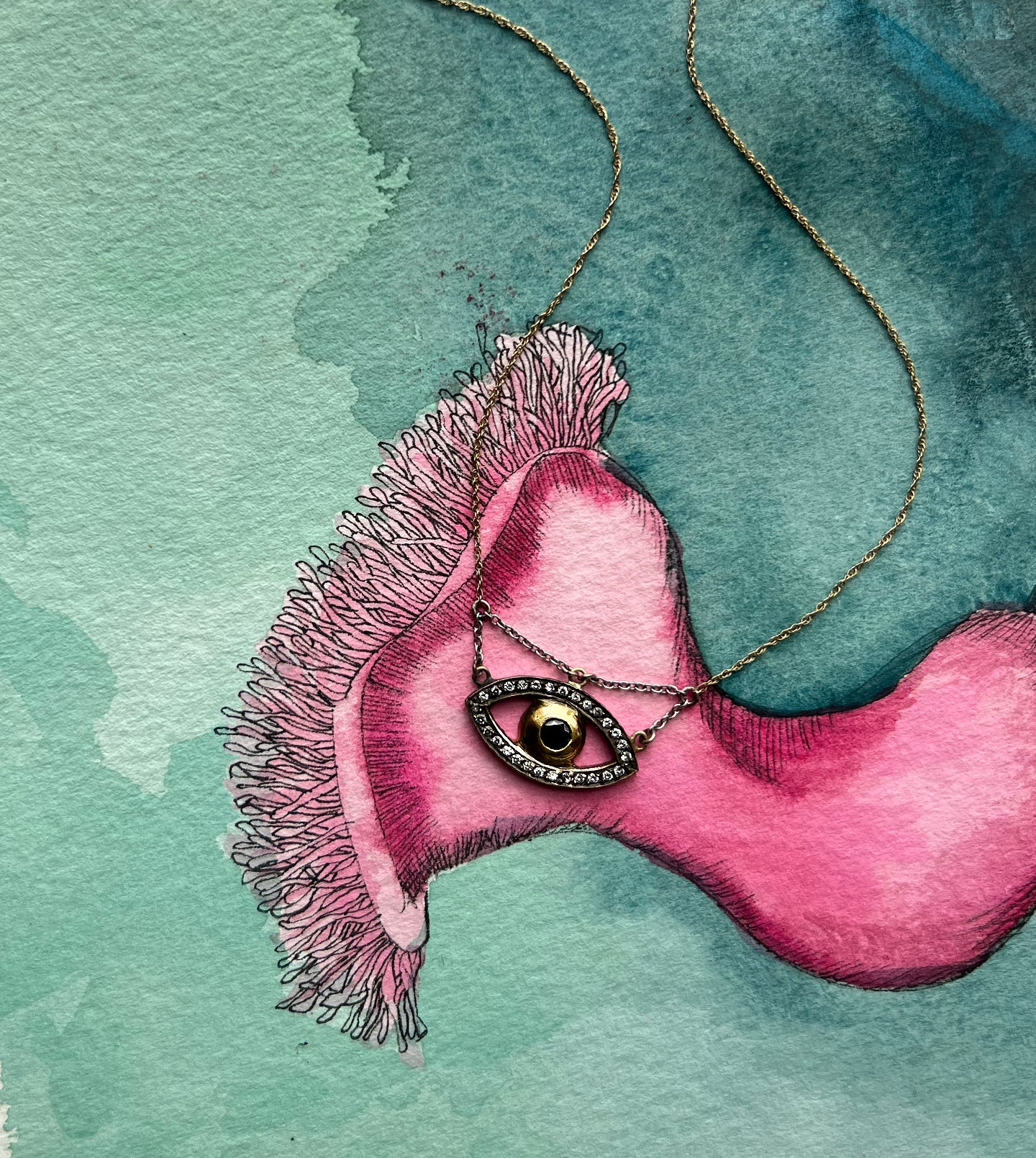 Evil eye pendant necklace shown over a pink-and-teal watercolor sketch