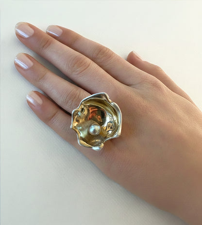 Large oyster cocktail ring with a pale gray pearl in a gold-and-silver shell, worn on a hand