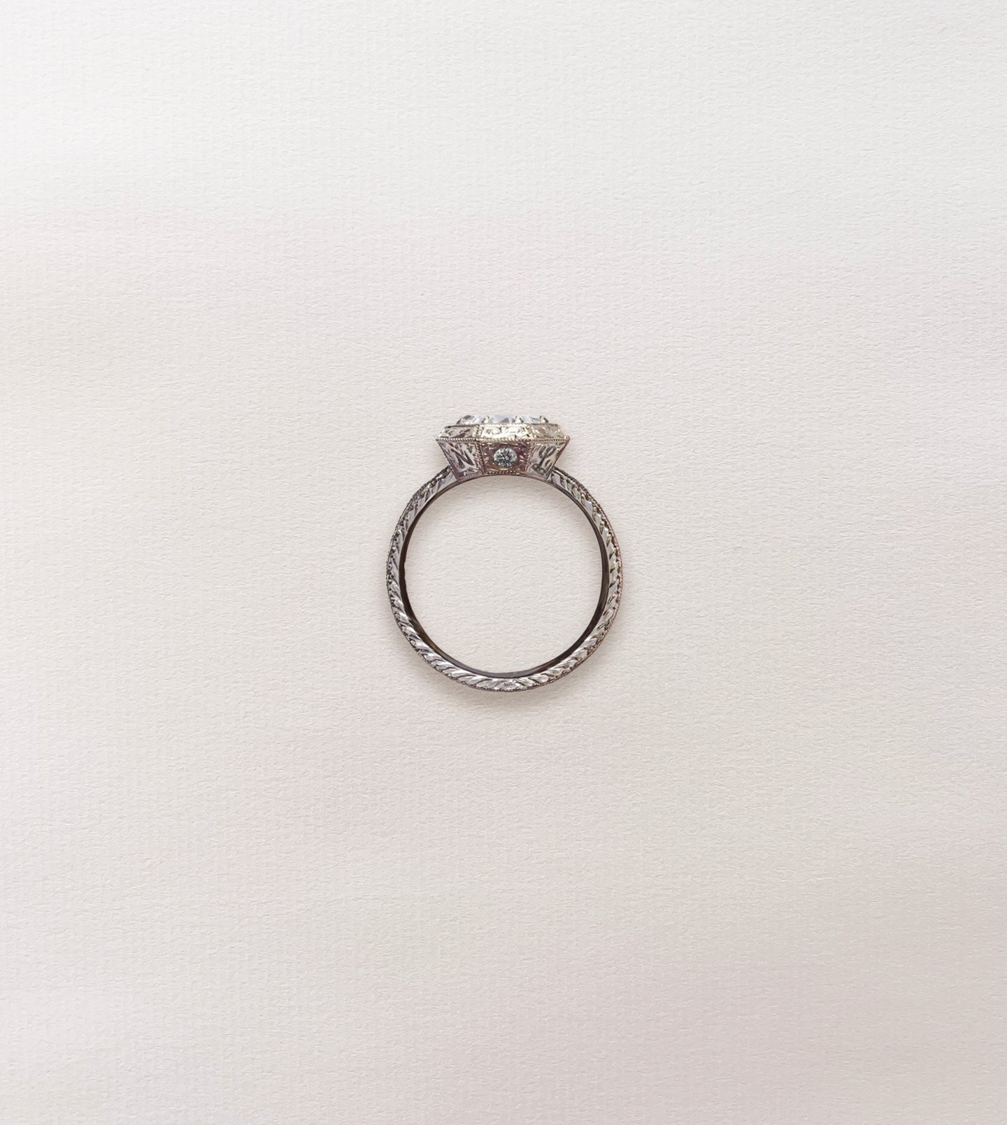 Side profile of an octagonal engagement ring with a hand-engraved band and round diamond