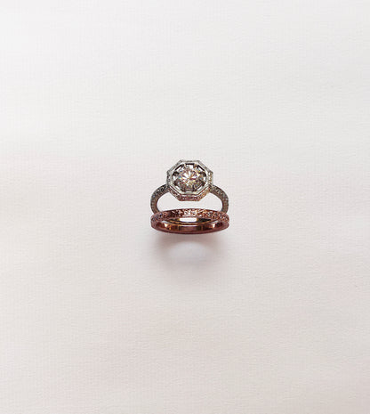 Octagonal engagement ring with a round diamond shown above its hand-engraved rose gold matching band