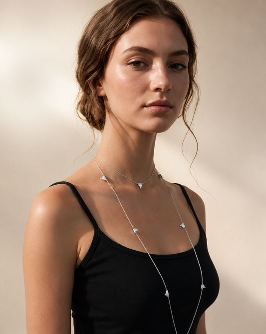 Woman wearing a black tank top with a long sterling silver rose thorn necklace.