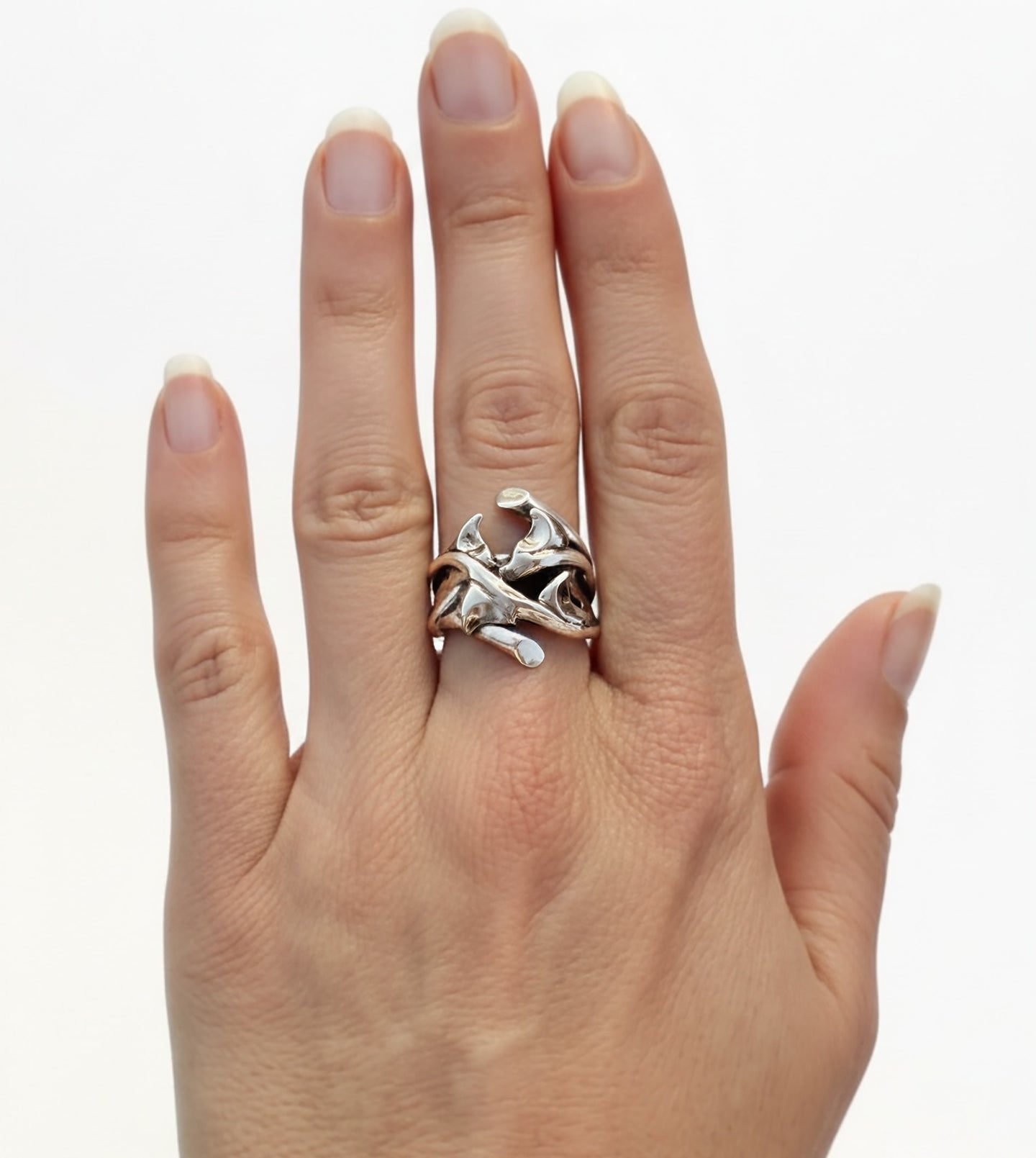 Polished sterling silver thorn ring worn on hand, showing the sculptural curves of hand-carved rose thorns
