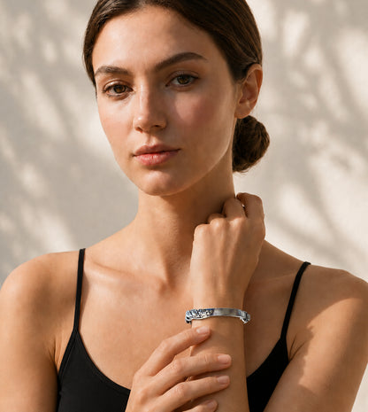 Woman wearing a black top and Twisting Vine Bracelet on wrist against a beige background