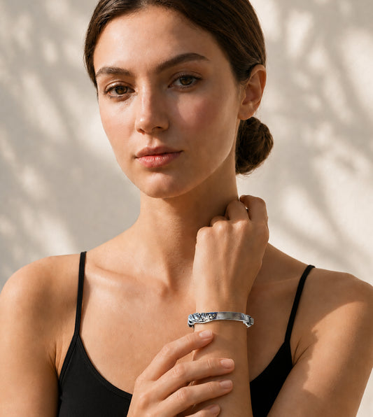 Woman wearing a black top and Twisting Vine Bracelet on wrist against a beige background