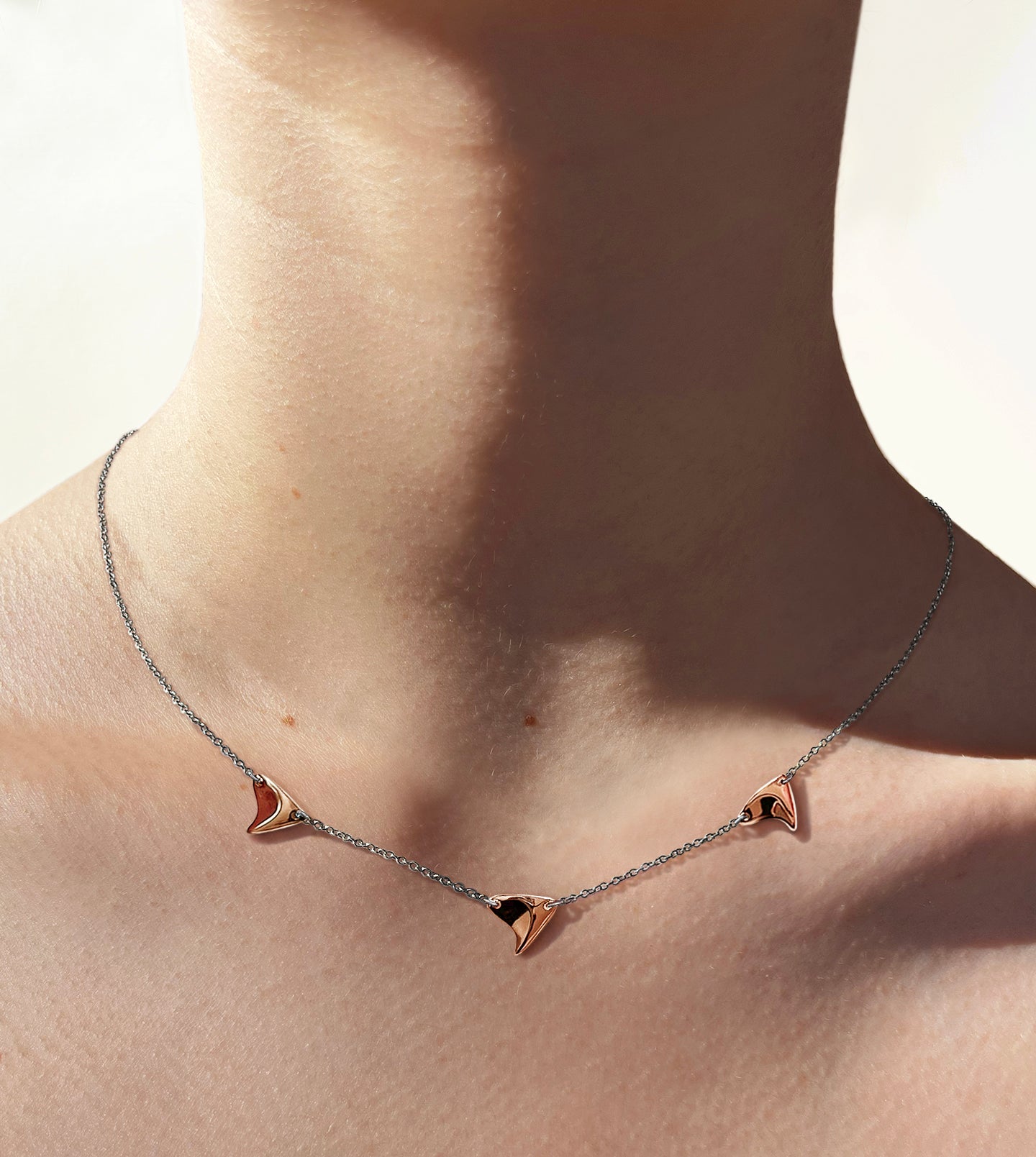 Three high shine rose gold thorns on delicate sterling silver chain on model's neck