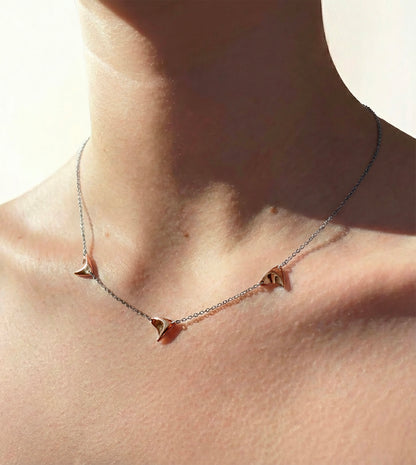 Three high shine rose gold thorns on delicate sterling silver chain on model's neck
