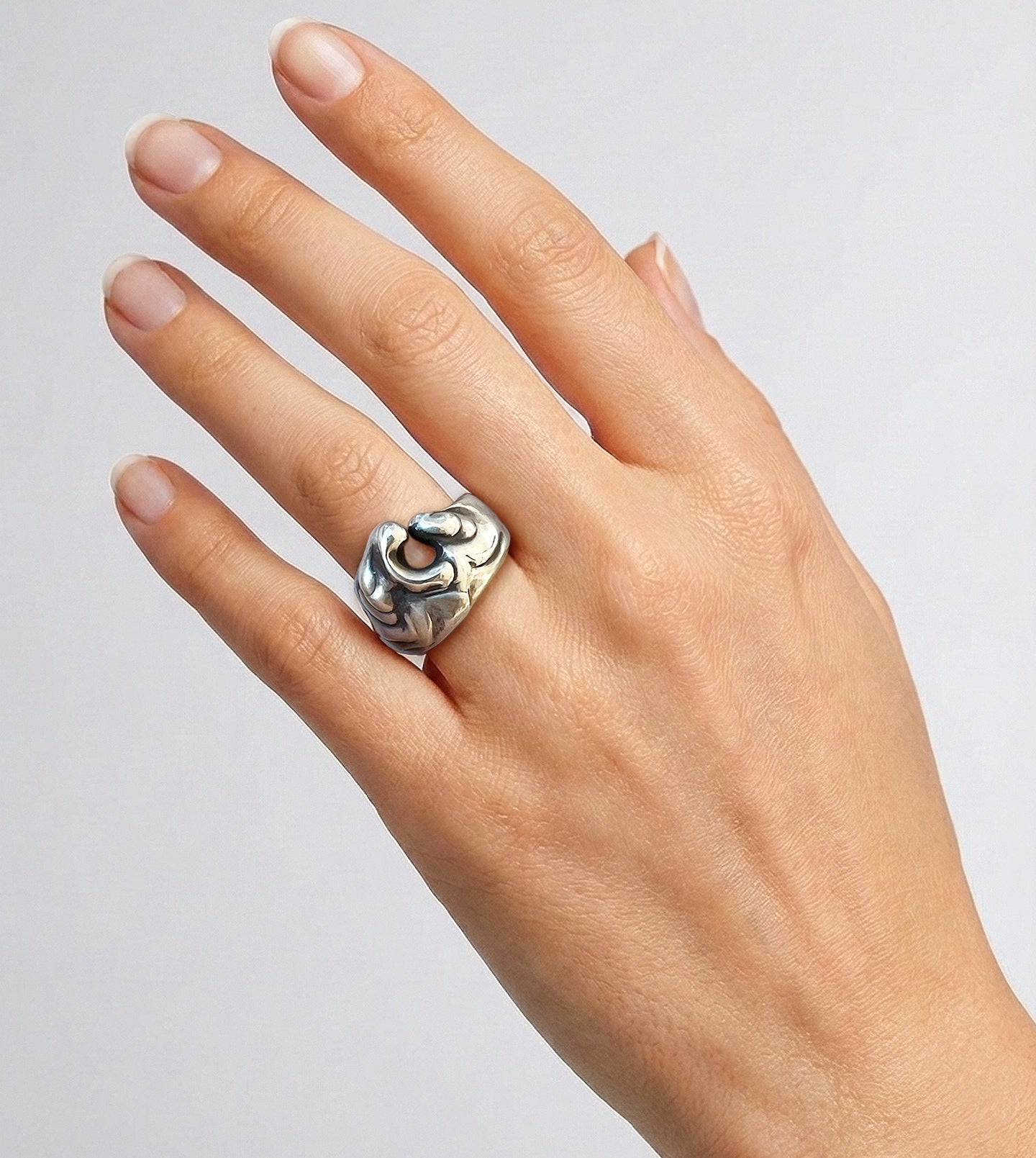 Hand wearing a brushed, blackened sterling silver wave ring