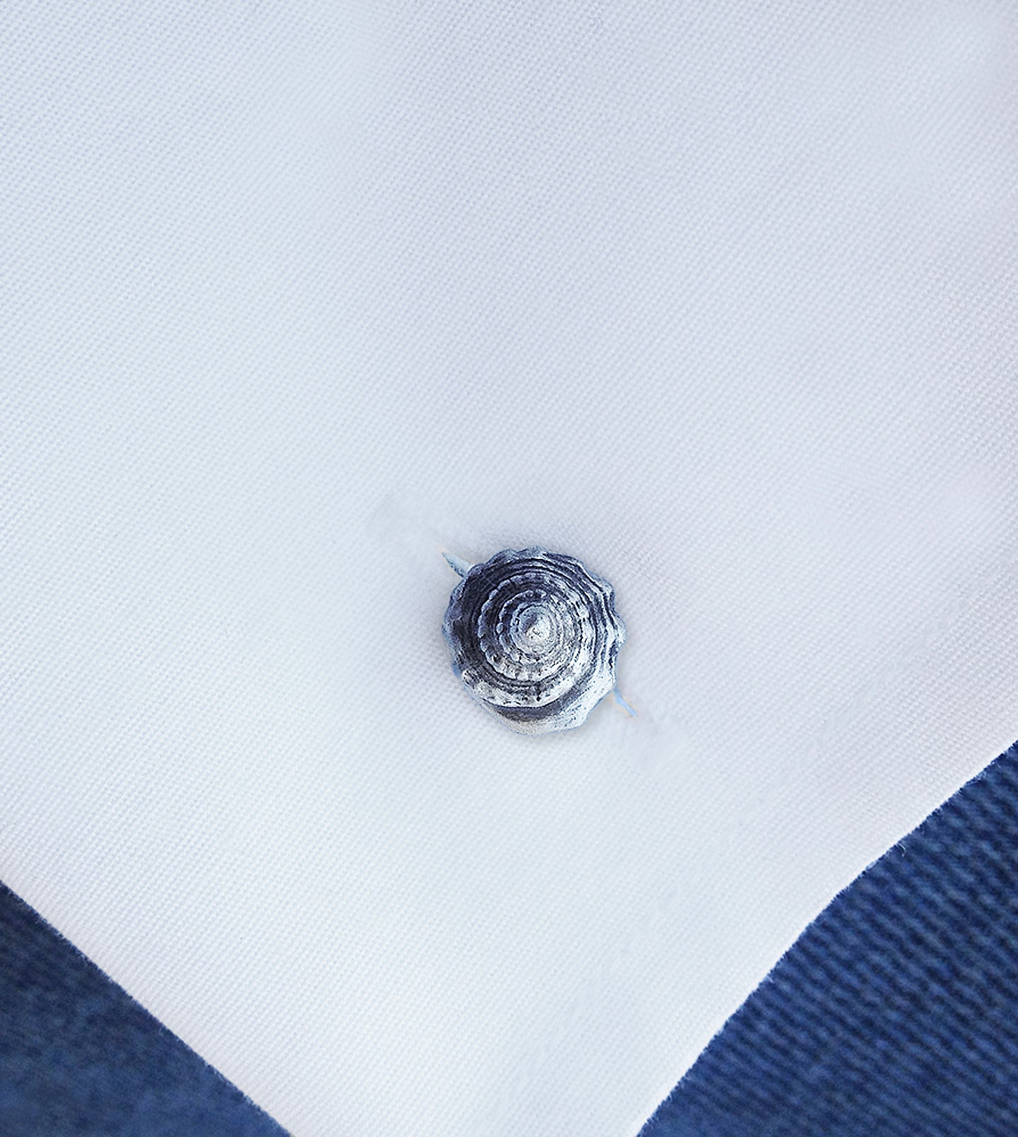 Oxidized sterling silver whelk shell cufflink worn on a white shirt cuff