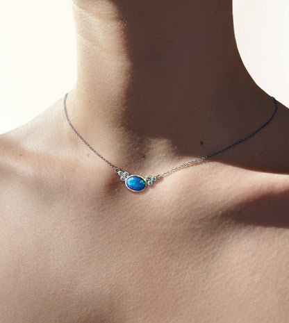 Opal and diamond necklace worn on the neck, blue-green opal in a gold bezel flanked by silver-set diamonds