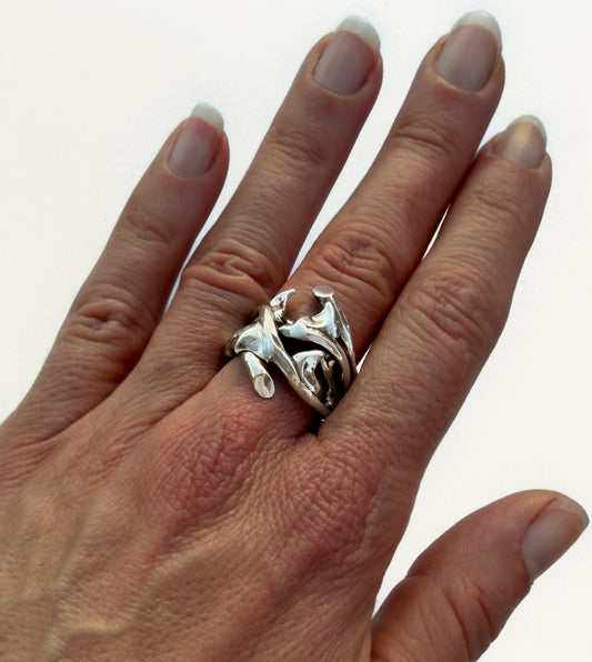 Hand-sculpted sterling silver rose thorn ring in high-shine polish, worn on woman's hand with organic curved thorns across the finger