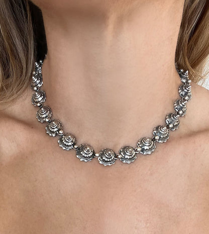 Blackened sterling silver shell necklace worn as a collar, interlocking whelk shell spires around the neck