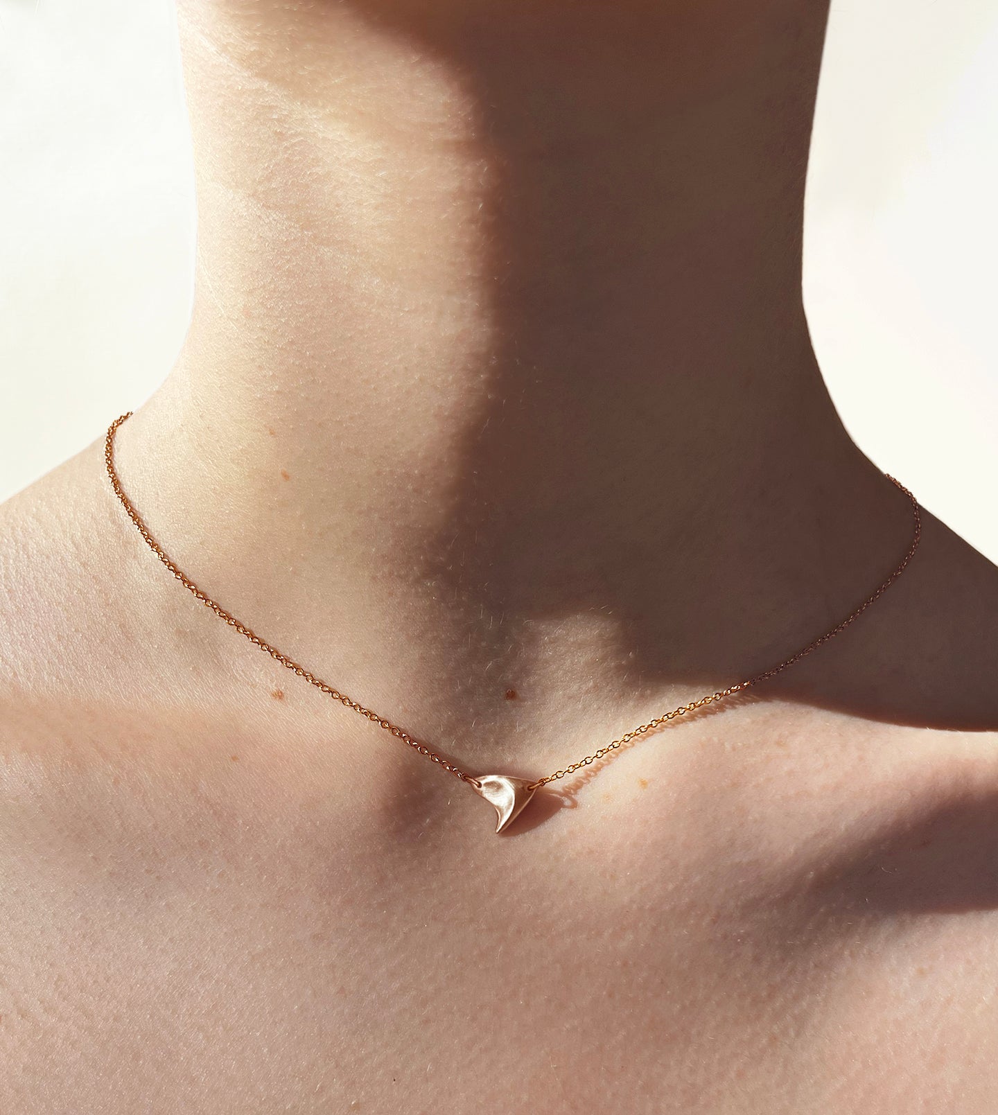 Rose gold brushed finish rose thorn on rose gold chain on model's neck