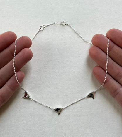 Sterling silver shiny finish triple rose thorn necklace on paper