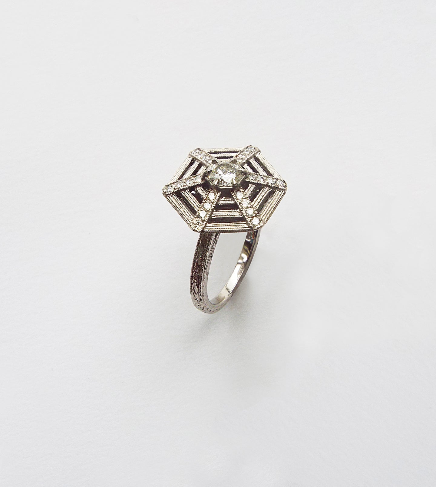Platinum spiderweb engagement ring with a central diamond and diamond-set web lines in a hexagonal frame