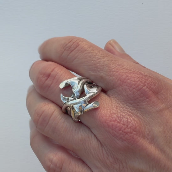 Close-up video of the hand-sculpted sterling silver Rose Thorn Ring in polished finish, rotating to show the curved thorn forms and how light moves across the sculpted surface.