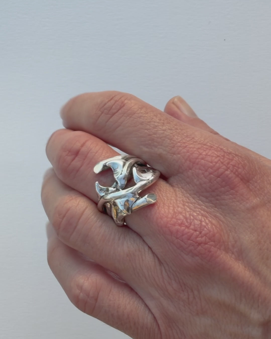 Close-up video of the hand-sculpted sterling silver Rose Thorn Ring in polished finish, rotating to show the curved thorn forms and how light moves across the sculpted surface.
